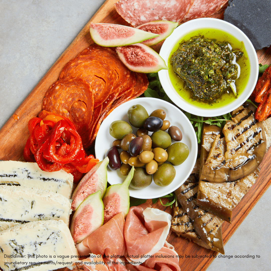 Wooden charcuterie board with bread, cheese, salami, olives, and crackers on a wooden surface.
