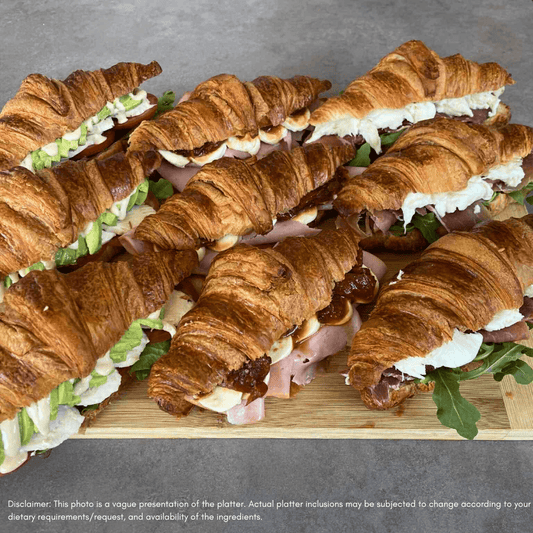 Platter of croissant sandwiches on a wooden board - coffs harbour catering company
